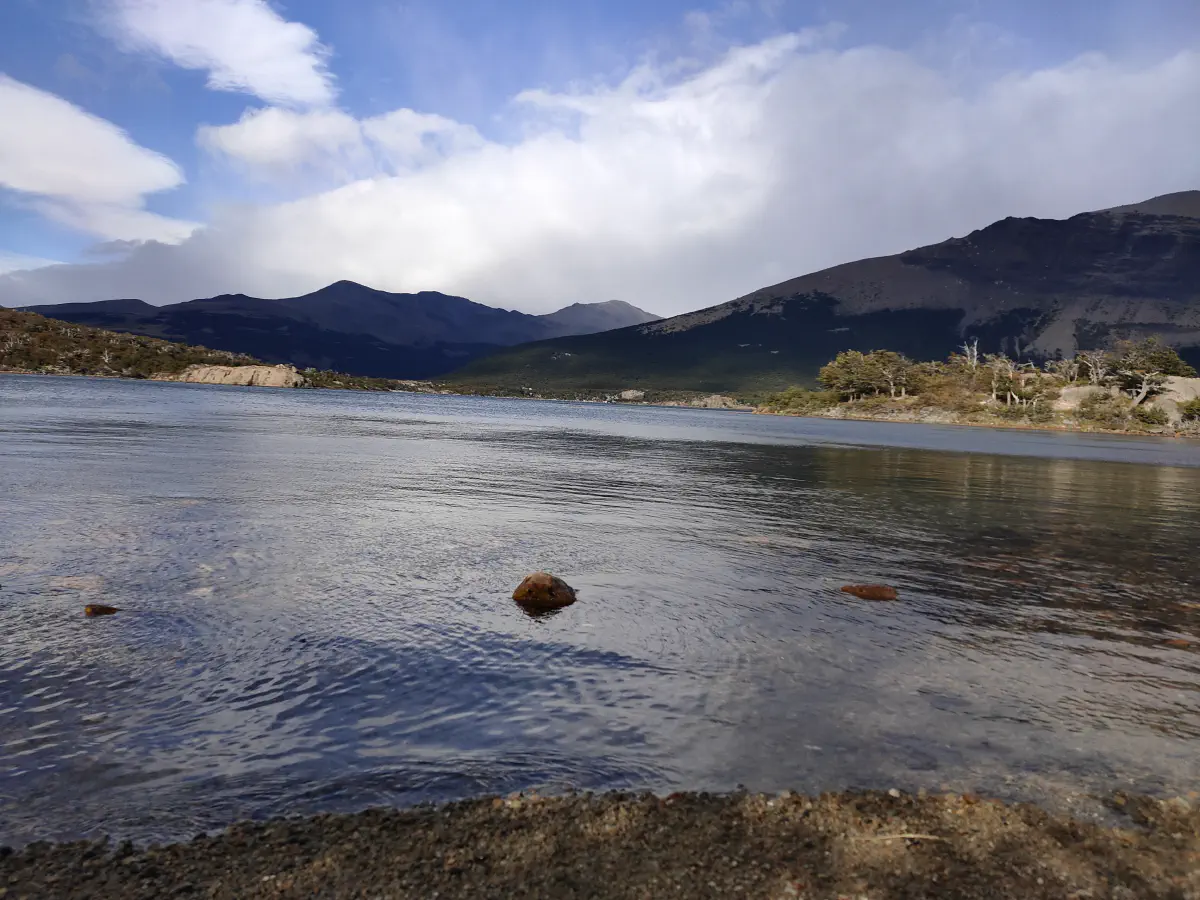 青い湖面が広がるアルヘンティノ湖と背後の山並みと積雲
