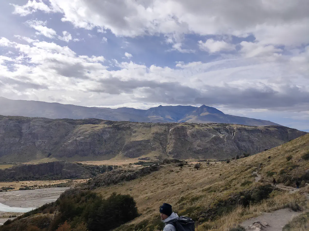ブエルタス川沿いの草原とパタゴニアの山並みを見る登山者