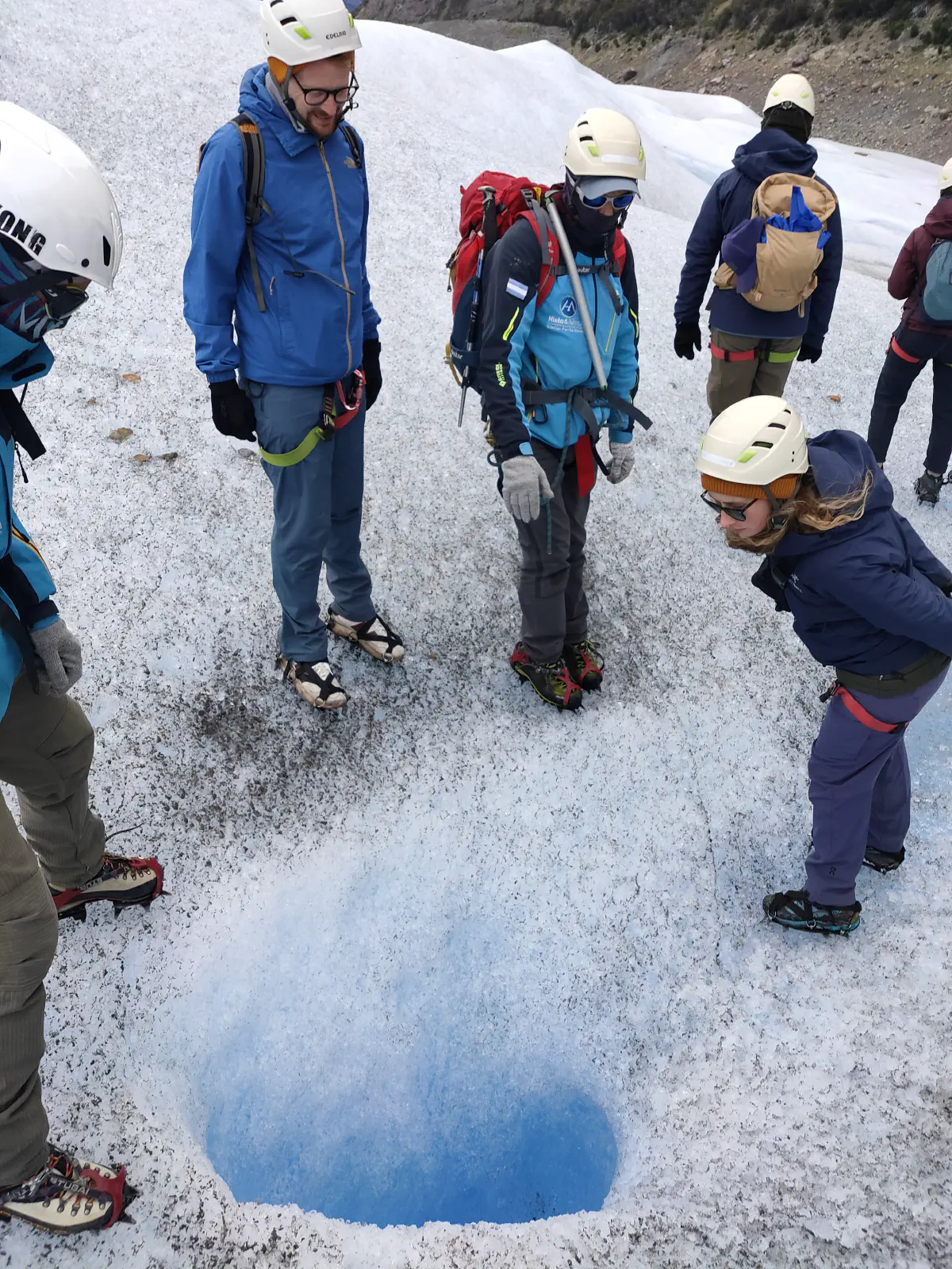 氷河の割れ目を恐る恐るのぞき込む女性
