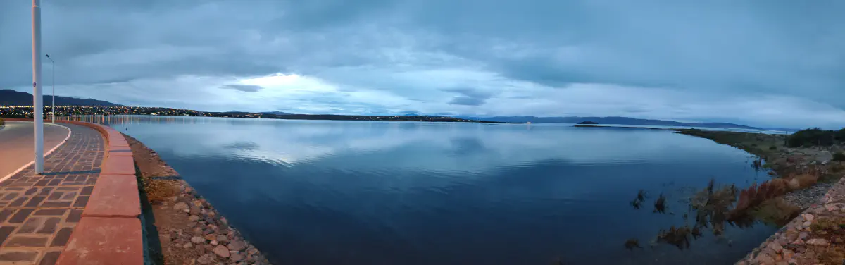 アルヘンティノ湖のパノラマと対岸の山並みを映す夕暮れの水面